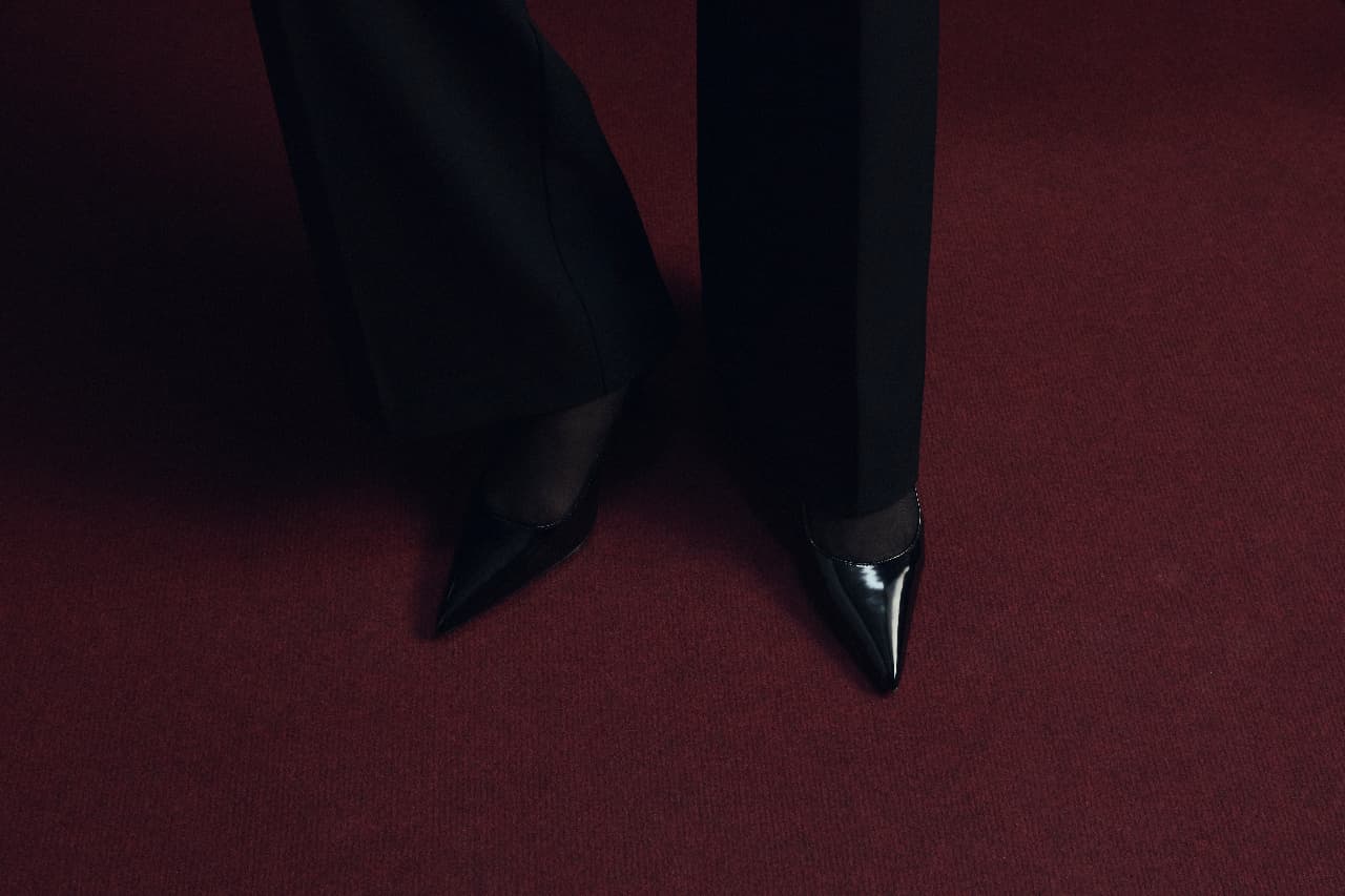 Black pointed pumps on a deep red carpet